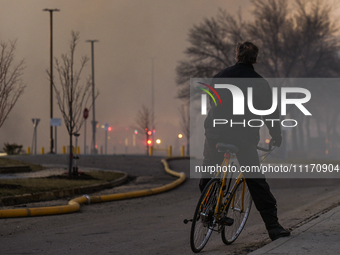 EDMONTON, CANADA - APRIL 22:
A man on his bike observes firefighters combating flames that tore through Edmonton's historic Hangar 11 on Mon...