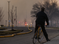 EDMONTON, CANADA - APRIL 22:
A man on his bike observes firefighters combating flames that tore through Edmonton's historic Hangar 11 on Mon...