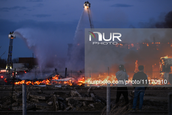 EDMONTON, CANADA - APRIL 22:
Two teenagers observe firefighters battling the flames that tore through Edmonton's historic Hangar 11 on Monda...