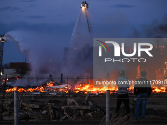 EDMONTON, CANADA - APRIL 22:
Two teenagers observe firefighters battling the flames that tore through Edmonton's historic Hangar 11 on Monda...