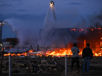 EDMONTON, CANADA - APRIL 22:
Two teenagers observe firefighters battling the flames that tore through Edmonton's historic Hangar 11 on Monda...