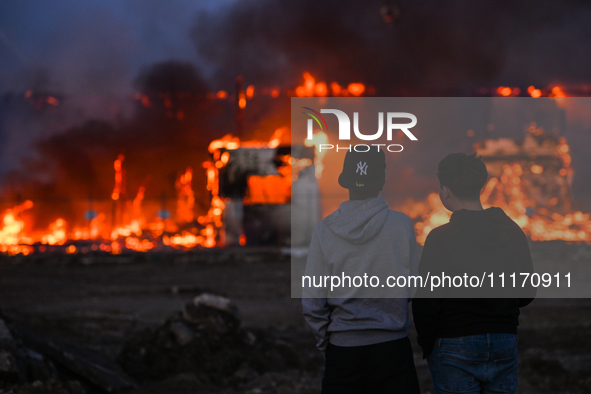 EDMONTON, CANADA - APRIL 22:
Two teenagers observe firefighters battling the flames that tore through Edmonton's historic Hangar 11 on Monda...