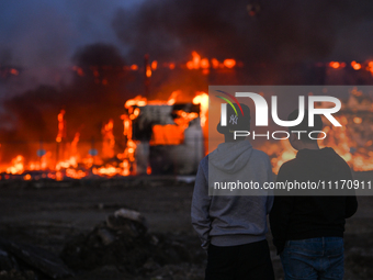 EDMONTON, CANADA - APRIL 22:
Two teenagers observe firefighters battling the flames that tore through Edmonton's historic Hangar 11 on Monda...