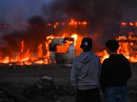 EDMONTON, CANADA - APRIL 22:
Two teenagers observe firefighters battling the flames that tore through Edmonton's historic Hangar 11 on Monda...