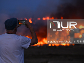 EDMONTON, CANADA - APRIL 22:
A local witnesses firefighters battling the flames that tore through Edmonton's historic Hangar 11 on Monday ev...