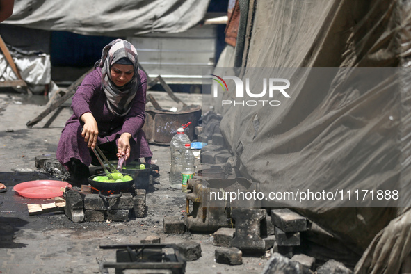 A displaced Palestinian woman, who has fled her home due to Israeli strikes, is looking on as she shelters in a UNRWA-affiliated school amid...