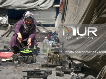 A displaced Palestinian woman, who has fled her home due to Israeli strikes, is looking on as she shelters in a UNRWA-affiliated school amid...