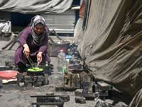 A displaced Palestinian woman, who has fled her home due to Israeli strikes, is looking on as she shelters in a UNRWA-affiliated school amid...