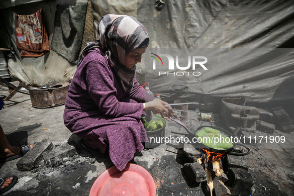 A displaced Palestinian woman, who has fled her home due to Israeli strikes, is looking on as she shelters in a UNRWA-affiliated school amid...