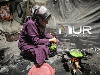 A displaced Palestinian woman, who has fled her home due to Israeli strikes, is looking on as she shelters in a UNRWA-affiliated school amid...