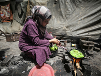 A displaced Palestinian woman, who has fled her home due to Israeli strikes, is looking on as she shelters in a UNRWA-affiliated school amid...