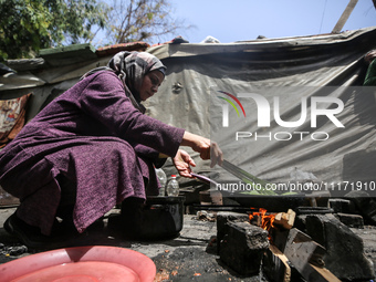 A displaced Palestinian woman, who has fled her home due to Israeli strikes, is looking on as she shelters in a UNRWA-affiliated school amid...