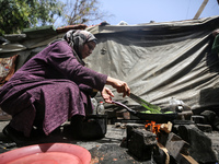 A displaced Palestinian woman, who has fled her home due to Israeli strikes, is looking on as she shelters in a UNRWA-affiliated school amid...