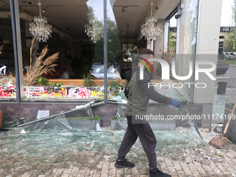 A man is removing broken glass in the Shevchenkivskyi district after a Russian missile attack in Kharkiv, Ukraine, on April 24, 2024. (