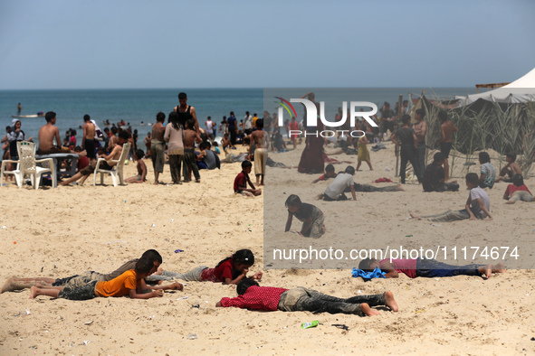 Palestinians are enjoying the beach on a hot day, amid the ongoing conflict between Israel and Hamas, in Deir Al-Balah, in the central Gaza...