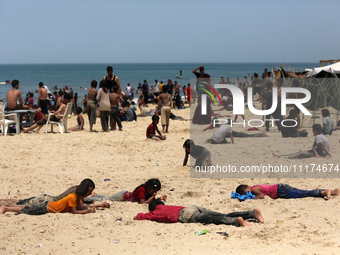 Palestinians are enjoying the beach on a hot day, amid the ongoing conflict between Israel and Hamas, in Deir Al-Balah, in the central Gaza...