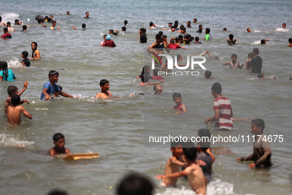 Palestinians are enjoying the beach on a hot day, amid the ongoing conflict between Israel and Hamas, in Deir Al-Balah, in the central Gaza...