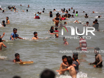 Palestinians are enjoying the beach on a hot day, amid the ongoing conflict between Israel and Hamas, in Deir Al-Balah, in the central Gaza...