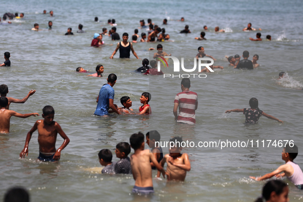 Palestinians are enjoying the beach on a hot day, amid the ongoing conflict between Israel and Hamas, in Deir Al-Balah, in the central Gaza...