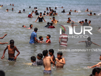 Palestinians are enjoying the beach on a hot day, amid the ongoing conflict between Israel and Hamas, in Deir Al-Balah, in the central Gaza...