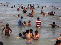 Palestinians are enjoying the beach on a hot day, amid the ongoing conflict between Israel and Hamas, in Deir Al-Balah, in the central Gaza...