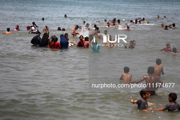 Palestinians are enjoying the beach on a hot day, amid the ongoing conflict between Israel and Hamas, in Deir Al-Balah, in the central Gaza...