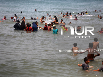 Palestinians are enjoying the beach on a hot day, amid the ongoing conflict between Israel and Hamas, in Deir Al-Balah, in the central Gaza...