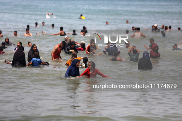 Palestinians are enjoying the beach on a hot day, amid the ongoing conflict between Israel and Hamas, in Deir Al-Balah, in the central Gaza...