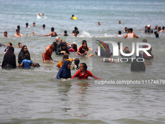 Palestinians are enjoying the beach on a hot day, amid the ongoing conflict between Israel and Hamas, in Deir Al-Balah, in the central Gaza...