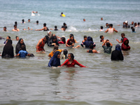 Palestinians are enjoying the beach on a hot day, amid the ongoing conflict between Israel and Hamas, in Deir Al-Balah, in the central Gaza...