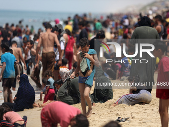 Palestinians are enjoying the beach on a hot day, amid the ongoing conflict between Israel and Hamas, in Deir Al-Balah, in the central Gaza...