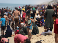 Palestinians are enjoying the beach on a hot day, amid the ongoing conflict between Israel and Hamas, in Deir Al-Balah, in the central Gaza...