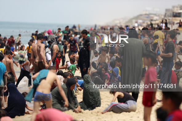 Palestinians are enjoying the beach on a hot day, amid the ongoing conflict between Israel and Hamas, in Deir Al-Balah, in the central Gaza...