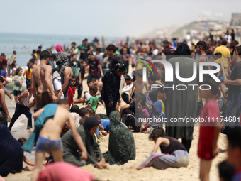 Palestinians are enjoying the beach on a hot day, amid the ongoing conflict between Israel and Hamas, in Deir Al-Balah, in the central Gaza...