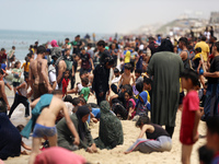 Palestinians are enjoying the beach on a hot day, amid the ongoing conflict between Israel and Hamas, in Deir Al-Balah, in the central Gaza...