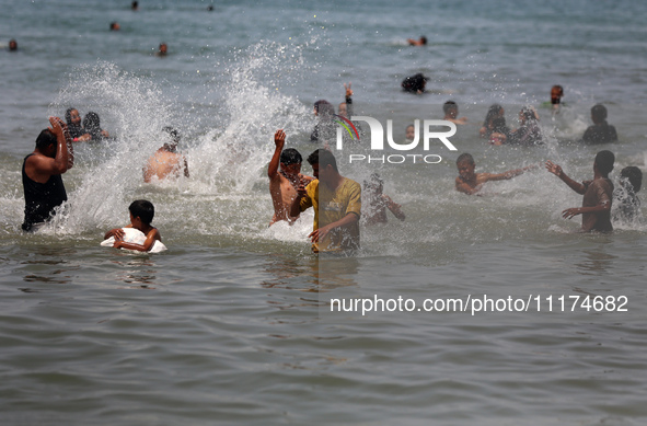 Palestinians are enjoying the beach on a hot day, amid the ongoing conflict between Israel and Hamas, in Deir Al-Balah, in the central Gaza...