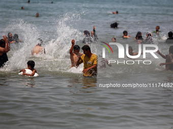 Palestinians are enjoying the beach on a hot day, amid the ongoing conflict between Israel and Hamas, in Deir Al-Balah, in the central Gaza...