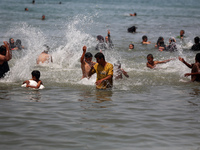 Palestinians are enjoying the beach on a hot day, amid the ongoing conflict between Israel and Hamas, in Deir Al-Balah, in the central Gaza...