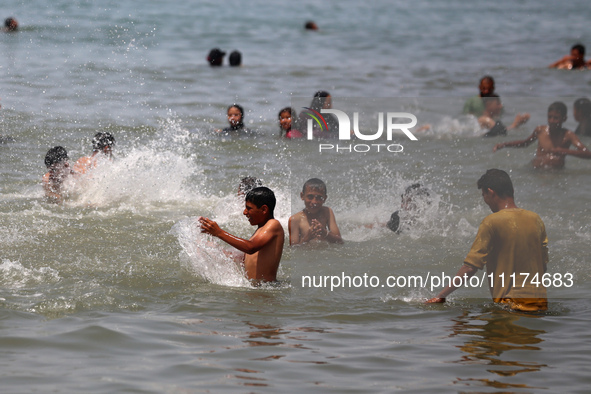 Palestinians are enjoying the beach on a hot day, amid the ongoing conflict between Israel and Hamas, in Deir Al-Balah, in the central Gaza...