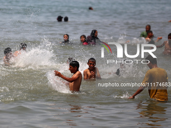 Palestinians are enjoying the beach on a hot day, amid the ongoing conflict between Israel and Hamas, in Deir Al-Balah, in the central Gaza...