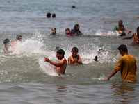 Palestinians are enjoying the beach on a hot day, amid the ongoing conflict between Israel and Hamas, in Deir Al-Balah, in the central Gaza...