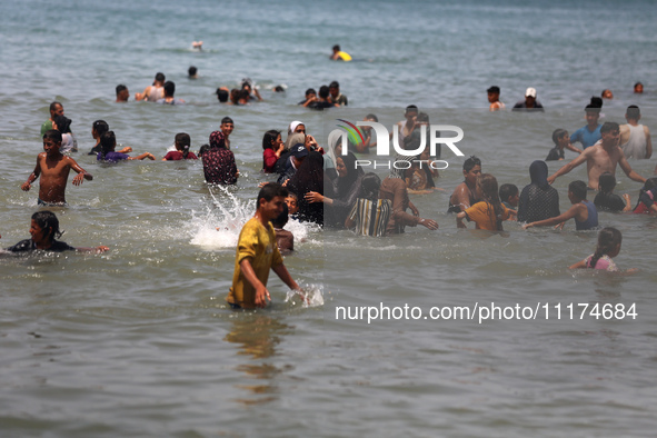 Palestinians are enjoying the beach on a hot day, amid the ongoing conflict between Israel and Hamas, in Deir Al-Balah, in the central Gaza...