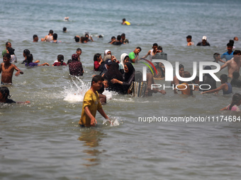 Palestinians are enjoying the beach on a hot day, amid the ongoing conflict between Israel and Hamas, in Deir Al-Balah, in the central Gaza...