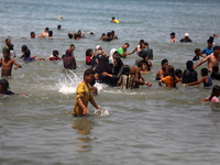 Palestinians are enjoying the beach on a hot day, amid the ongoing conflict between Israel and Hamas, in Deir Al-Balah, in the central Gaza...