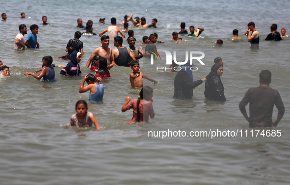 Palestinians are enjoying the beach on a hot day, amid the ongoing conflict between Israel and Hamas, in Deir Al-Balah, in the central Gaza...