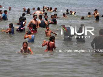 Palestinians are enjoying the beach on a hot day, amid the ongoing conflict between Israel and Hamas, in Deir Al-Balah, in the central Gaza...