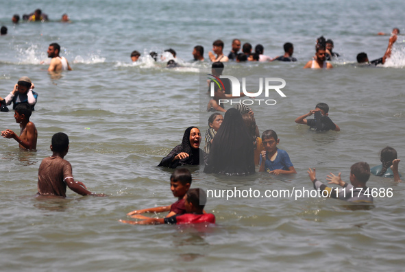 Palestinians are enjoying the beach on a hot day, amid the ongoing conflict between Israel and Hamas, in Deir Al-Balah, in the central Gaza...