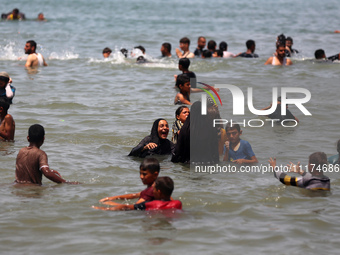 Palestinians are enjoying the beach on a hot day, amid the ongoing conflict between Israel and Hamas, in Deir Al-Balah, in the central Gaza...