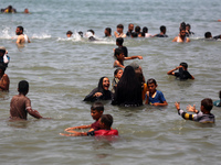 Palestinians are enjoying the beach on a hot day, amid the ongoing conflict between Israel and Hamas, in Deir Al-Balah, in the central Gaza...