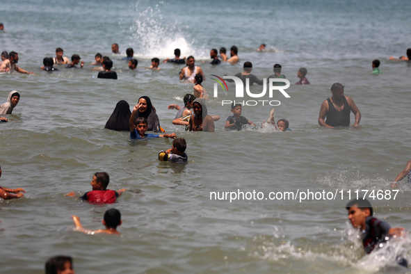 Palestinians are enjoying the beach on a hot day, amid the ongoing conflict between Israel and Hamas, in Deir Al-Balah, in the central Gaza...